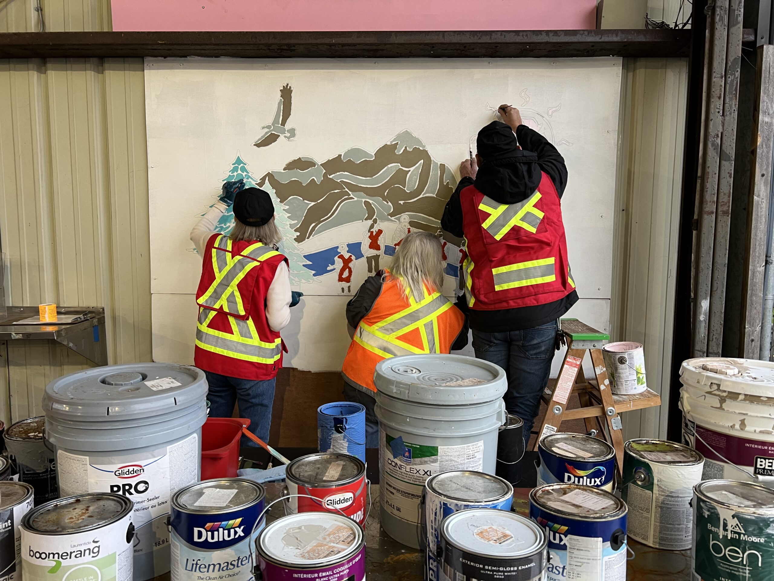 Volunteers in safety vests painting the community mural together.