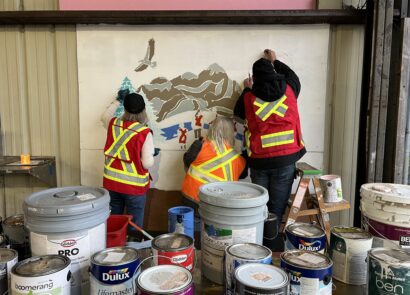 Volunteers in safety vests painting the community mural together.